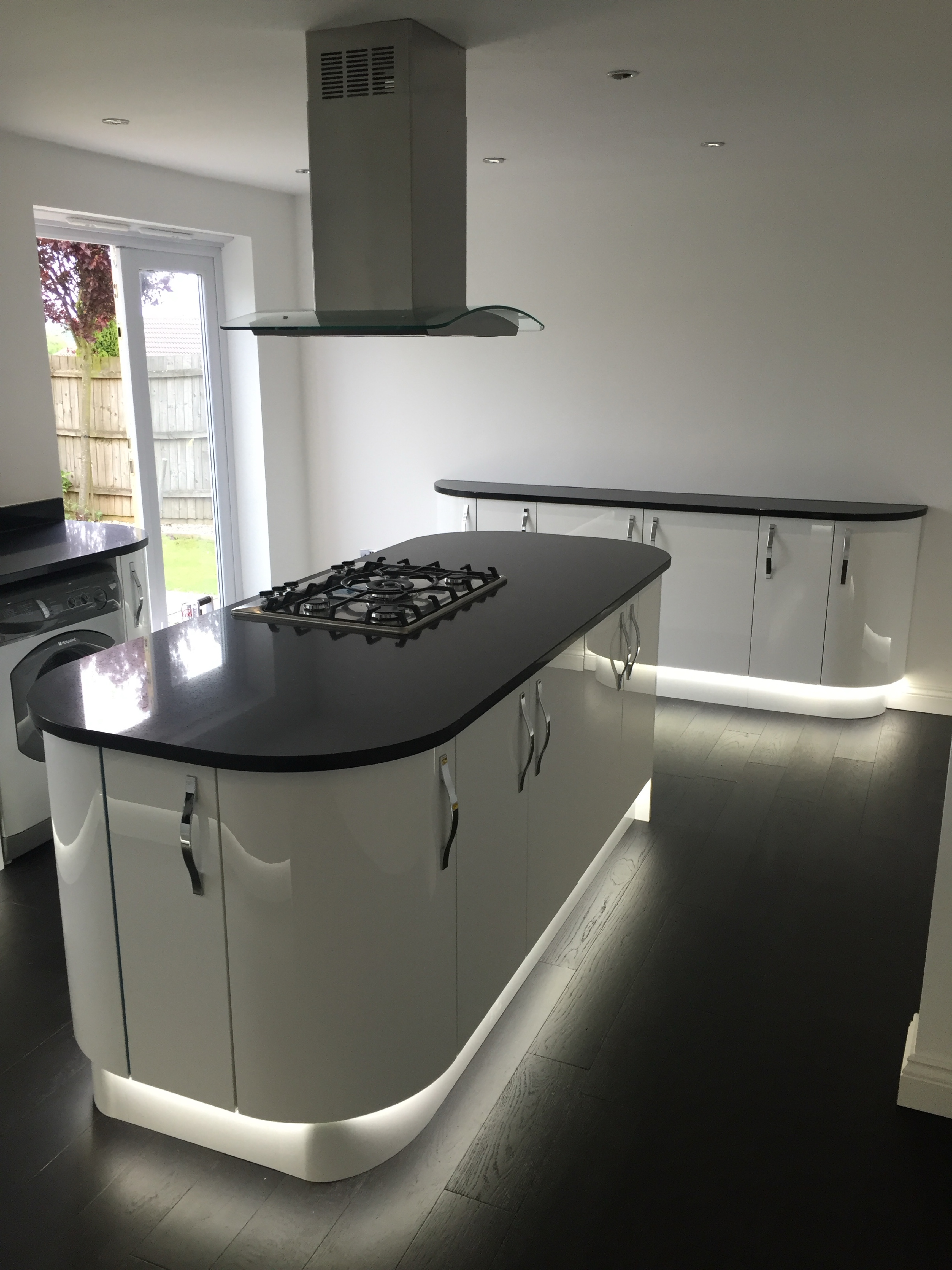Glossy white curved kitchen cabinets with ambient lighting