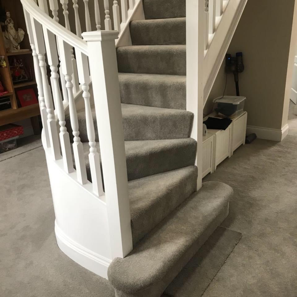 Curved white staircase with carpeted steps and turned spindles